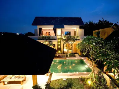 a house with a swimming pool at night at Villa Cokelat in Canggu
