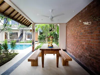 a patio with a table and benches next to a brick wall at Villa Cokelat in Canggu