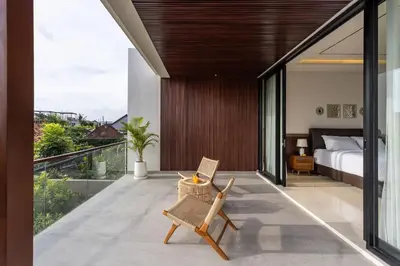 a bedroom with a bed and a chair on a balcony at Pristine & Modern Gem Luxury 3bd Villa in Umalas in Kerobokan