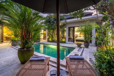 a swimming pool with two chairs and an umbrella at Villa Eleni - Your Private Oasis in Seminyak - A Hosted Luxury Boutique Villa in Seminyak
