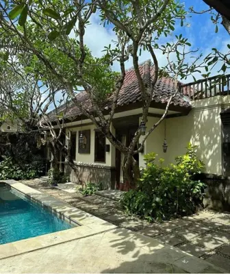 a house with a swimming pool in front of it at Villa Gadja Bali in Jimbaran