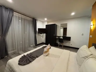 a bedroom with a large white bed and a piano at Hotel ARA Legian in Legian