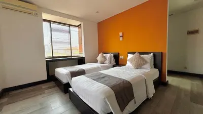 two beds in a room with an orange wall at Hotel ARA Legian in Legian