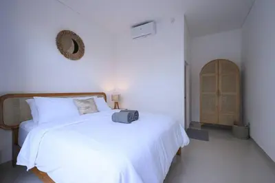 a bedroom with a white bed with a suitcase on it at Eunoia Villa in Jimbaran
