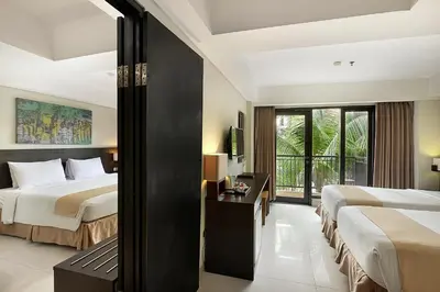 a hotel room with two beds and a balcony at Rofa Kuta Hotel - CHSE Certified in Legian