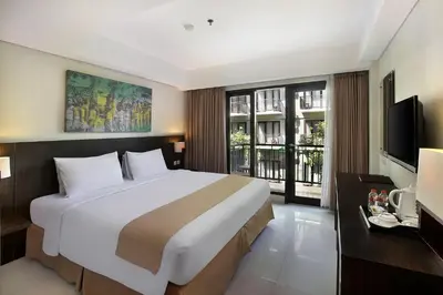 a hotel room with a large bed and a television at Rofa Kuta Hotel - CHSE Certified in Legian