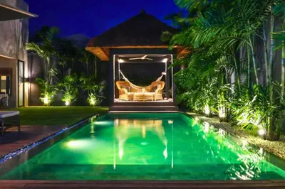 a swimming pool in the backyard of a house at night at Bintarti 3 BR Private Pool Villa in Canggu