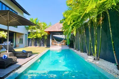 a swimming pool in front of a villa with palm trees at Bintarti 3 BR Private Pool Villa in Canggu