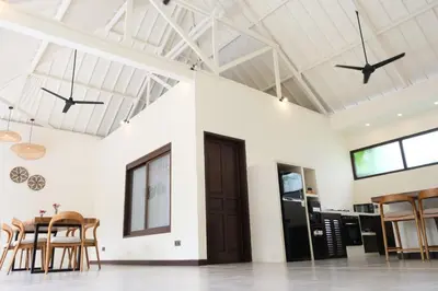 a dining room with white walls and wooden chairs at Uma dharma villas in Seminyak