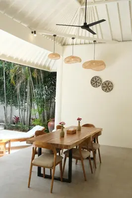 a dining room with a wooden table and chairs at Uma dharma villas in Seminyak