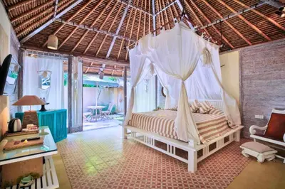 a bedroom with a bed with a mosquito net at Vanshika 1 BR Garden Villa Shared Pool in Sanur