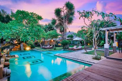 a swimming pool in a resort with palm trees at Vanshika 1 BR Garden Villa Shared Pool in Sanur