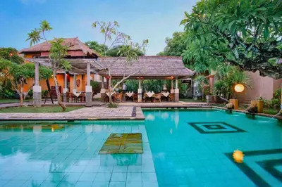 a swimming pool in front of a house at Vanshika 1 BR Garden Villa Shared Pool in Sanur