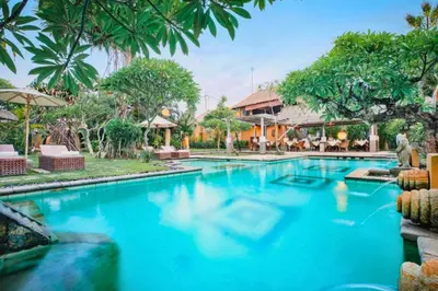a pool at a resort with blue water and palm trees at Vanshika 1 BR Garden Villa Shared Pool in Sanur