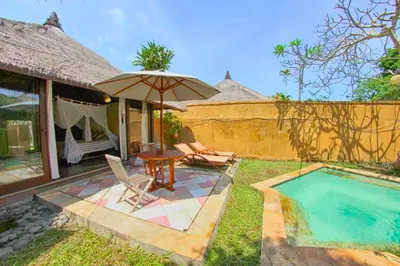 a patio with a table and an umbrella next to a pool at Vainavi 1 BR Private Pool Villa in Sanur