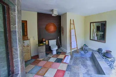 a bathroom with a toilet and a tile floor at Vainavi 1 BR Private Pool Villa in Sanur