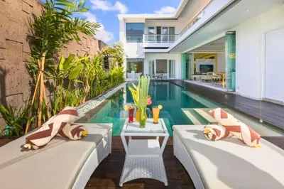 a swimming pool with two chaise lounges next to a house at Lashana 3 BR Private Pool Villa in Legian