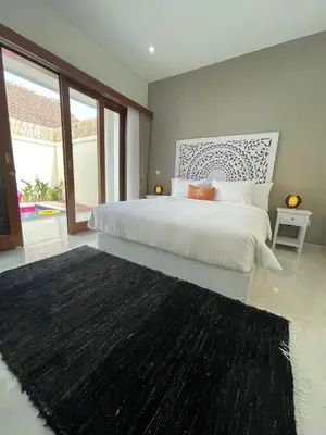 a bedroom with a large bed with a black rug at CASA NOOA Kerobokan in Kerobokan