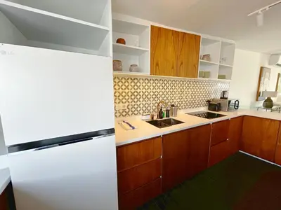 a kitchen with a white refrigerator and wooden cabinets at The Cruise Berawa - Design Apartments & Penthouses by CPM Bali in Canggu
