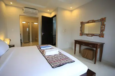 a bedroom with a bed and a desk and a mirror at Nyoman Villa Sanur in Sanur