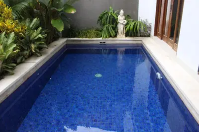 a swimming pool with blue water in a yard at Nyoman Villa Sanur in Sanur