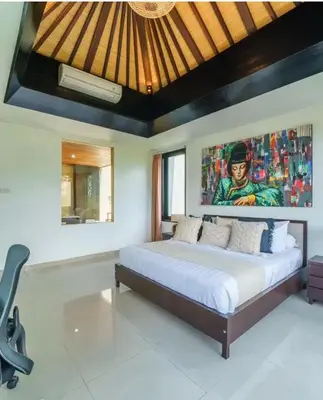 a bedroom with a large bed with a painting on the wall at Villa J in Nusa Dua