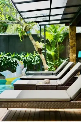 a patio with lounge chairs and a swimming pool at Villa J in Nusa Dua