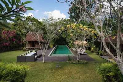 a garden with a swimming pool and trees at Moments Villa in Jimbaran