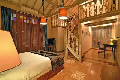 a bedroom with a bed and a desk and a staircase at Moments Villa in Jimbaran