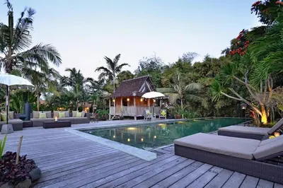 a resort swimming pool with a house in the background at Moments Villa in Jimbaran