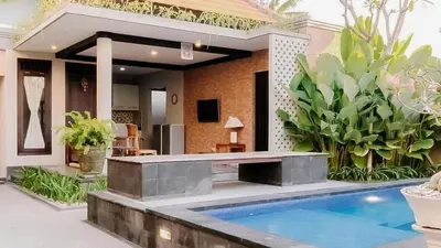 a house with a swimming pool in front of it at arimanu rooms in Kuta