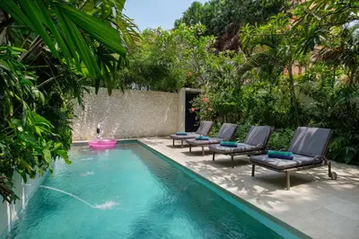 a swimming pool with lounge chairs and a fountain at Villa Levi by GORO in Seminyak