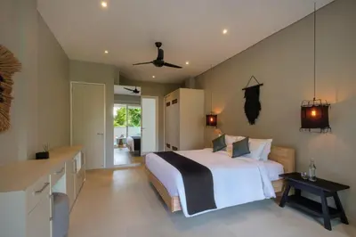 a bedroom with a large bed and a kitchen at Villa Levi by GORO in Seminyak