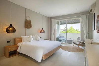a bedroom with a large white bed and a living room at Villa Levi by GORO in Seminyak