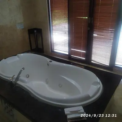 a white bath tub in a bathroom with windows at Private villa with swimming pool in Kuta