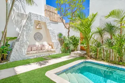 a backyard with a swimming pool and palm trees at Villa Aztec - 6BDR private pool and garden in Seminyak