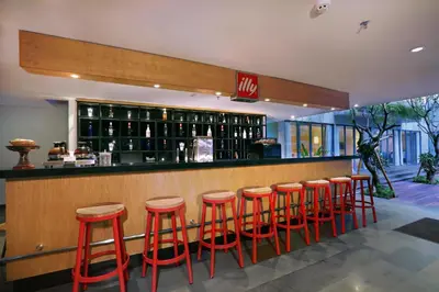 a bar with red stools in a restaurant at Hotel NEO+ Kuta Legian by ASTON in Legian