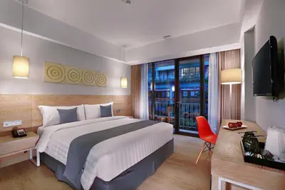 a hotel room with a large bed and a television at Hotel NEO+ Kuta Legian by ASTON in Legian