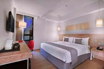 a hotel room with a large bed and a television at Hotel NEO+ Kuta Legian by ASTON in Legian