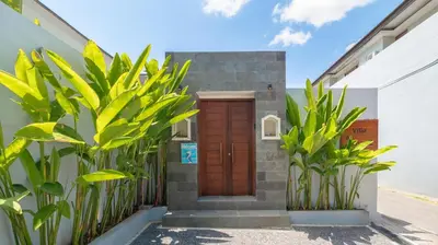 a house with a wooden door and some plants at Villa Lange 2 by Villa Finder in Seminyak