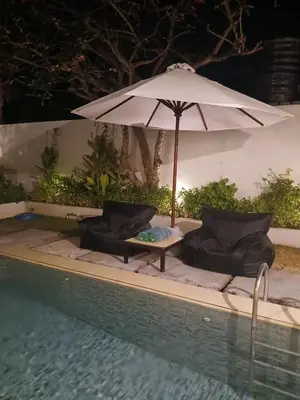 an umbrella and chairs next to a swimming pool at Village Pool Private In Kuta Bali in Legian