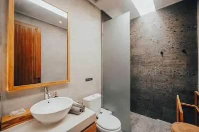 a bathroom with a sink and a toilet and a mirror at Villa Cintamu - Modern Spacious Villa in Prime Berawa Location in Canggu