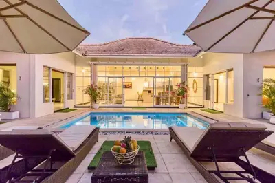 a house with a swimming pool and two chairs at Spacious 2bdr Seminyak walking eat&shop street in Seminyak