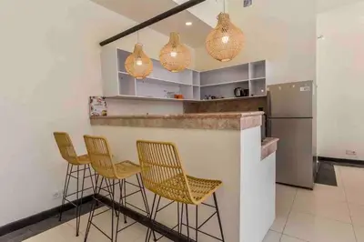 a kitchen with a bar with chairs and a refrigerator at Spacious 2bdr Seminyak walking eat&shop street in Seminyak