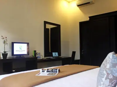 a bedroom with a bed with a television and a desk at Nakula Stay Kuta in Kuta