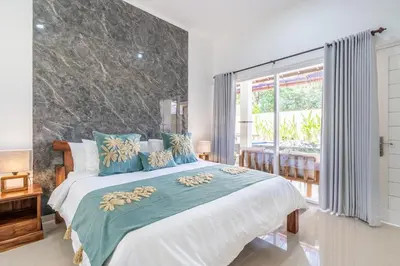 a bedroom with a large bed with blue pillows at Rumah Kodel in Legian in Seminyak