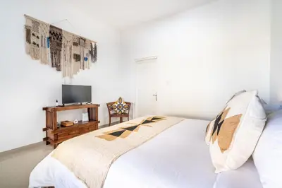 a white bedroom with a bed and a tv at Rumah Kodel in Legian in Seminyak