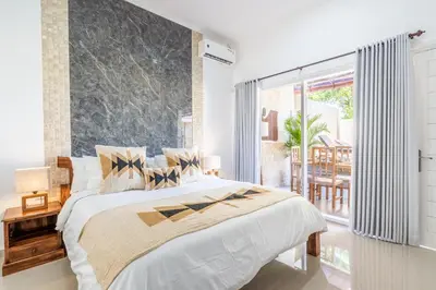 a bedroom with a large bed and a large window at Rumah Kodel in Legian in Seminyak