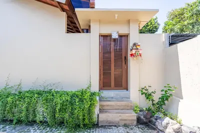 a white house with a wooden door and stairs at Rumah Kodel in Legian in Seminyak