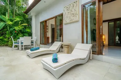 a patio with white furniture and a table and chairs at Villa Nemia Seminyak in Seminyak